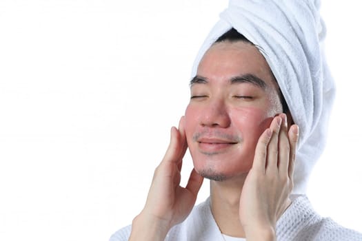 Handsome man with closed eyes applying moisturizer on his face carefully after laser resurfacing.