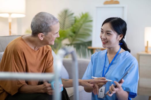 Asian caregiver using a digital tablet with an elderly woman at home, highlighting elderly care and the use of digital health tools