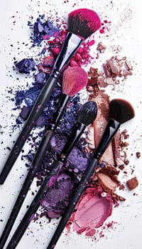 Makeup brushes with colorful eyeshadow and blush on a white background.