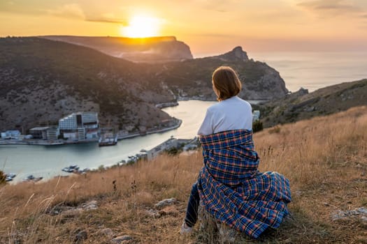 Happy woman on sunset in mountains. Woman siting with her back on the sunset in nature in summer. Silhouette