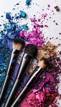 A close-up image of three makeup brushes covered in various colors of eyeshadow and blush on a white background.