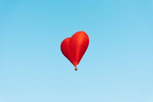 red heartshaped balloon soaring against a backdrop of clear blue sky