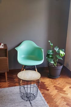 The living room features a green chair and a wooden dresser, adding a touch of nature with a houseplant in a flowerpot. The interior design blends furniture with the buildings wood flooring