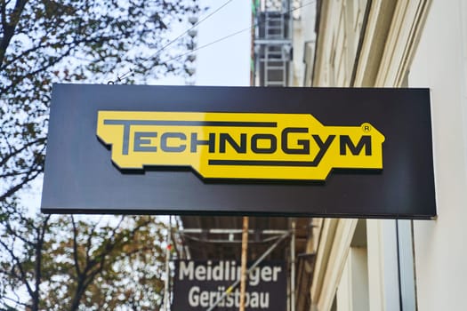 A sleek technogym sign hangs from the side of the building, contrasting against the sky. The rectangular signage stands out with modern font