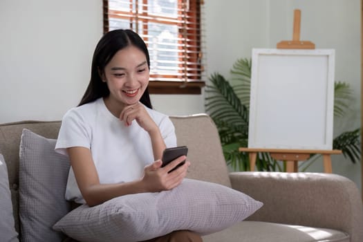 A woman sitting on a sofa using her smartphone, illustrating the concept of modern communication and digital connectivity in a comfortable home setting