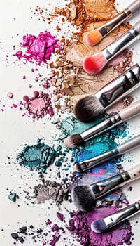 Close-up of various makeup brushes covered in colorful eyeshadow and blush against a white background.