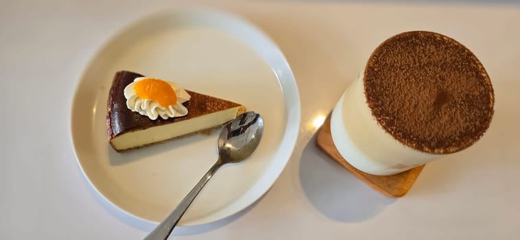 Lemon cheesecake freshly baked slice, New York style classical cheese cake on dessert plate background. Slice of tasty cake on white plate served with dessert spoon, good for cooking book