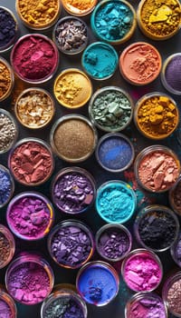 A close-up view of various colorful makeup pigments and powders in small glass jars, arranged in an artistic pattern.