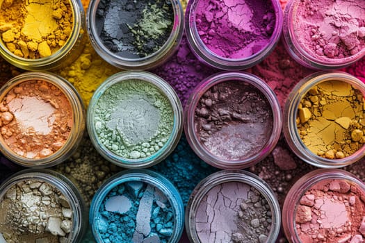 A close-up shot of various colorful makeup pigments and powders arranged in small glass jars.