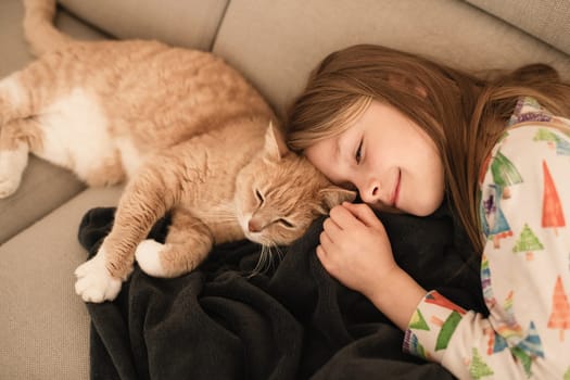 A girl near a ginger cat on the sofa