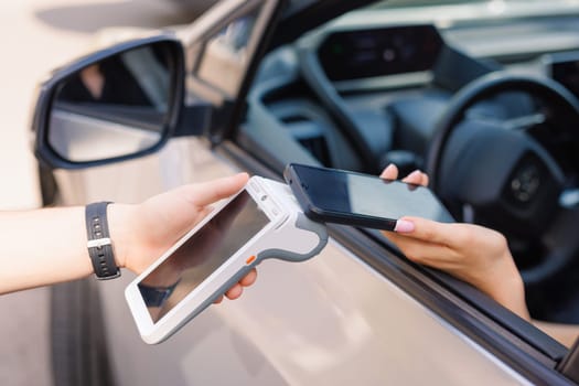 girl driver makes NFC payment with her mobile phone, contactless payment method for services, online payments