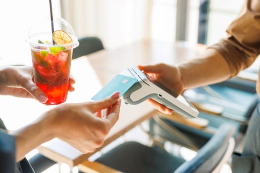 NFC credit card payment. Woman paying with contactless credit card with NFC technology. Wireless money transaction. Card machine in male hand on sunlight background