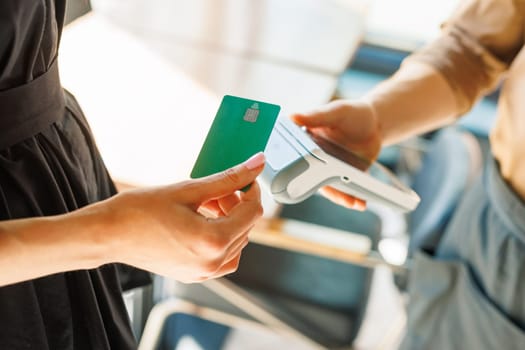 NFC credit card payment. Woman paying with contactless credit card with NFC technology. Wireless money transaction. Card machine in male hand on sunlight background