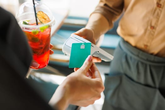 NFC credit card payment. Woman paying with contactless credit card with NFC technology. Wireless money transaction. Card machine in male hand on sunlight background