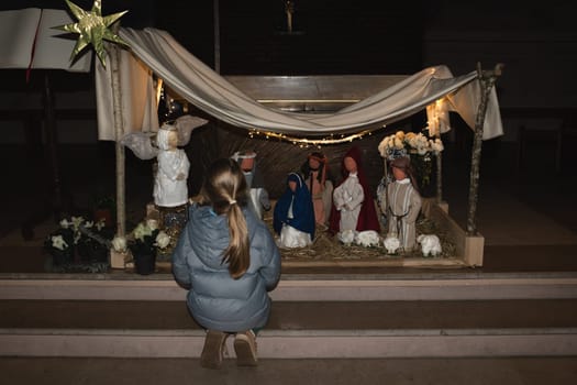 Girl is looking at a Christmas nativity scene with baby Jesus Creche Figurines