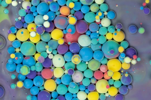 A close-up photograph showcasing a mesmerizing array of colorful bubbles suspended in a liquid medium, creating a stunning abstract composition. The bubbles exhibit a vibrant spectrum of hues.