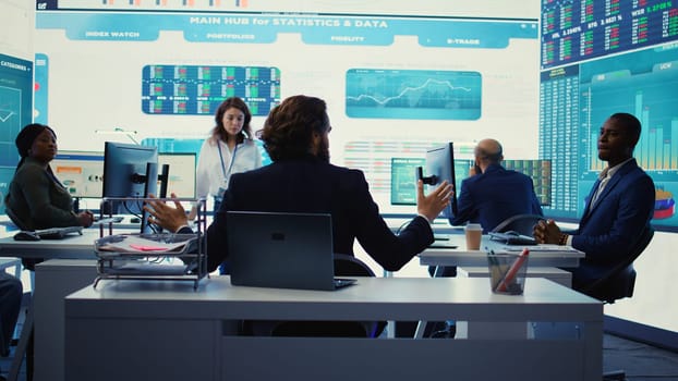 Chairman of the advisory board transmits potential company expansion plans, supervisor and the staff look into data visualizations on a big screen. Teamwork to boost affordable earnings. Camera B.