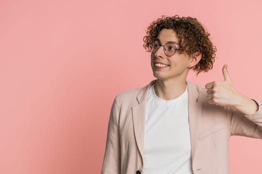 Like. Caucasian man raises thumbs up agrees with something or gives positive reply recommends advertisement likes good idea feedback celebrating success victory. Guy isolated on pink background