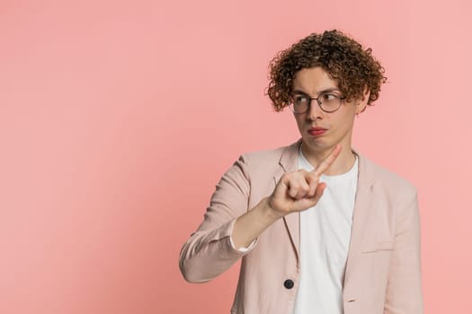 Displeased upset curly haired man in jacket reacting to unpleasant awful idea, dissatisfied with bad quality, wave hand, shake head No, dismiss idea, don't like proposal. Young guy on pink background