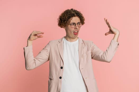 Disappointed Caucasian curly haired man in jacket showing blah blah nonsense gesture with hands, not interested in conversation, gossips, empty promises, rumors, liars. Guy isolated on pink background