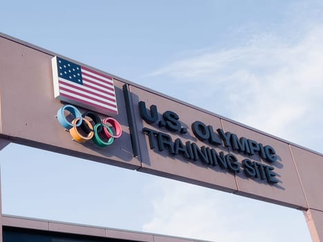 Colorado Springs, Colorado, USA-May 13, 2024-A detailed shot of the entrance sign for the U.S. Olympic Training Site, featuring the American flag and Olympic rings under a clear sky.