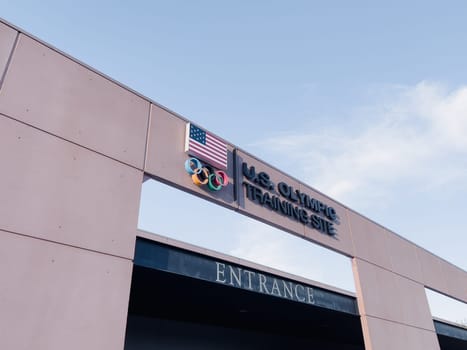 Colorado Springs, Colorado, USA-May 13, 2024-A detailed shot of the entrance sign for the U.S. Olympic Training Site, featuring the American flag and Olympic rings under a clear sky.