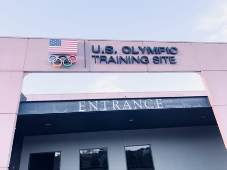 Colorado Springs, Colorado, USA-May 13, 2024-A detailed shot of the entrance sign for the U.S. Olympic Training Site, featuring the American flag and Olympic rings under a clear sky.