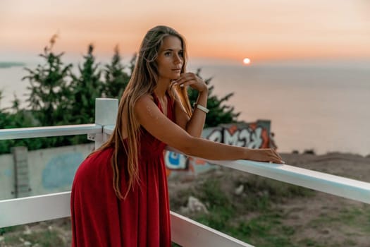 Woman sunset sea red dress, portrait happy beautiful sensual woman in a red long dress posing above the sea on sunset