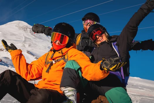 A group of young people enjoy their vacation in the mountains in winter. Hipsters in ski clothes happy while skiing and snowboarding.