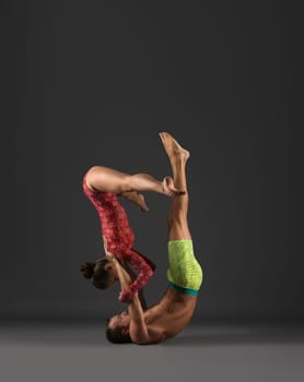 Sport. Duo of gymnasts exercising at camera, on gray background