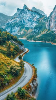 A picturesque scene of a road traversing a lake amidst mountains under the open sky as seen from above