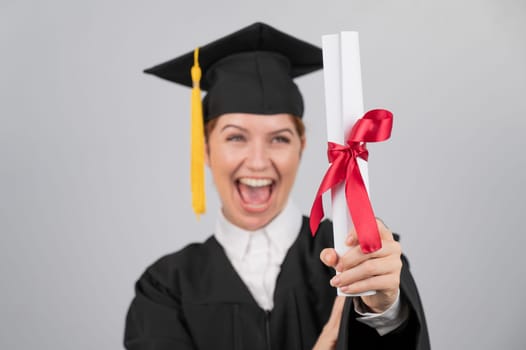 Emotional woman in graduate gown holding diploma in foreground