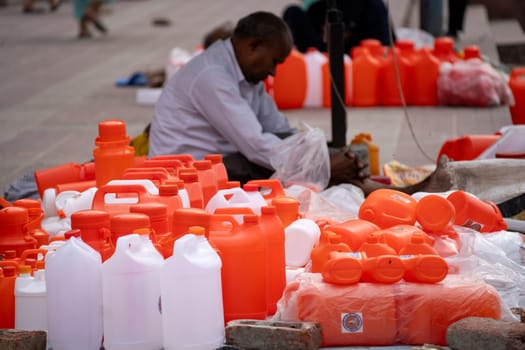 Haridwar, India - 30th Apr 2023: Shopkeeper selling saffron white water bottles used to fill holy water from river ganga for prayers and rituals