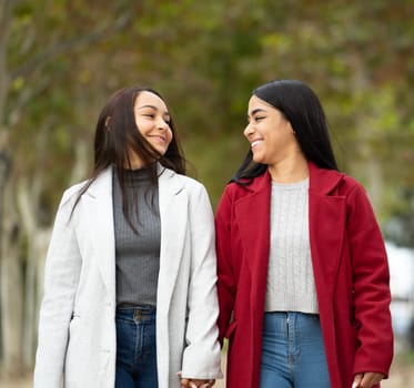 Front view of lesbian latin couple in love smiling looking at each other , holding hands in a park.LGBT family.