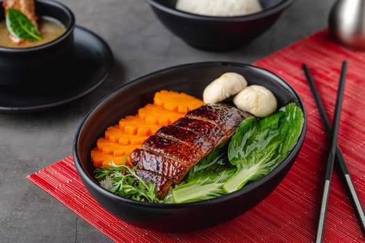 Roast duck with rice and teriyaki sauce on black plate