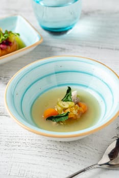 Fish soup with vegetables on white wooden table