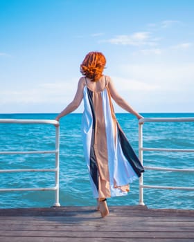 Behind girl on pier. Woman in colorfull dress standing on the pier.