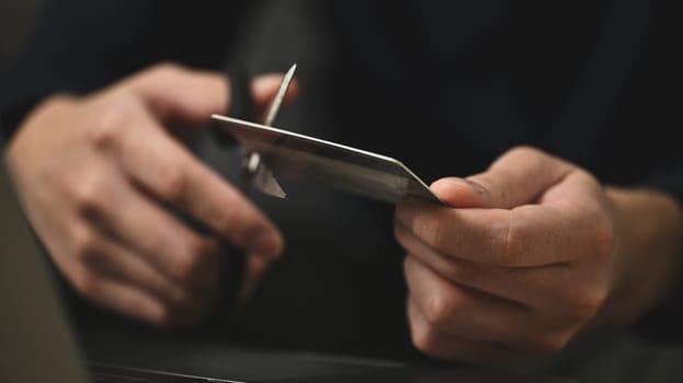 Young man cutting credit card with scissors. Financial problems concept.