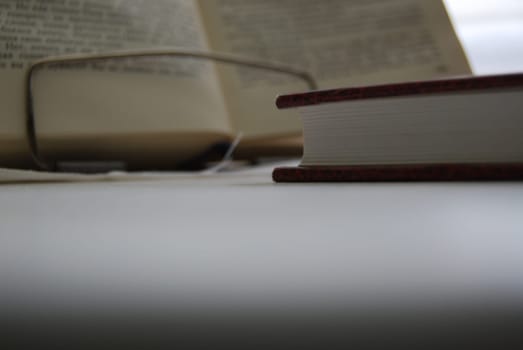 There is a book on the table, and in the background there is a stand with an open book.