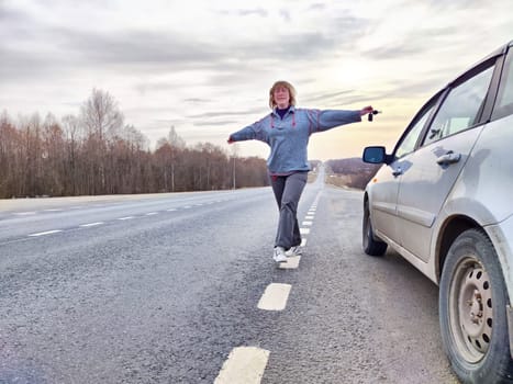 Woman Balancing on Road Marking During Roadside Travel Break. Woman enjoying playful balance walk next to parked car on roadside