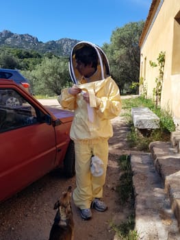 A beekeeper in a protective suit just returning from work on a summer day.