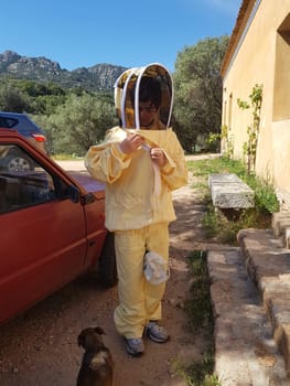 A beekeeper in a protective suit just returning from work on a summer day.