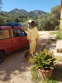 A beekeeper in a protective suit just returning from work on a summer day.