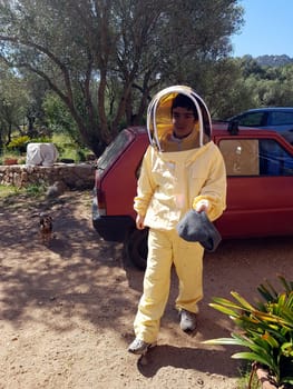 A beekeeper in a protective suit just returning from work on a summer day.