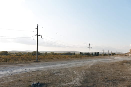 Rural landscape with winding dirt road and power lines stretching into the distance