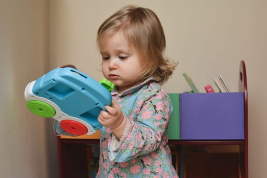A two year old girl plays with toys in a childrens room