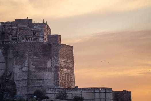 mehrangarh fort in Jodhpur Rajasthan sitting on hilltop surrounded by orange monsoon clouds showing the landmark in India