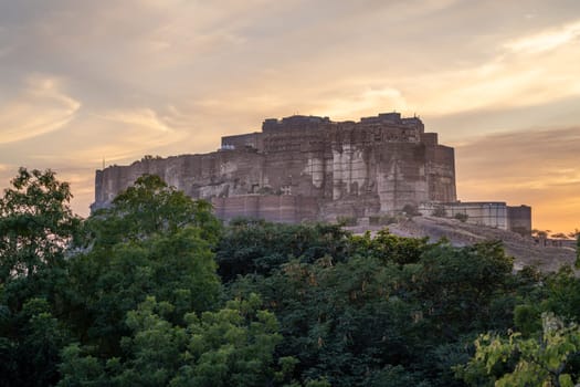 mehrangarh fort in Jodhpur Rajasthan sitting on hilltop surrounded by orange monsoon clouds showing the landmark in India