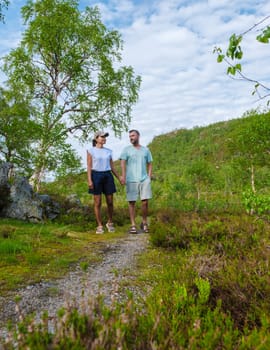 A couple walks hand-in-hand along a path in a Norwegian forest, enjoying the fresh air and natural beauty of the surroundings. men and women walking in forest in summer