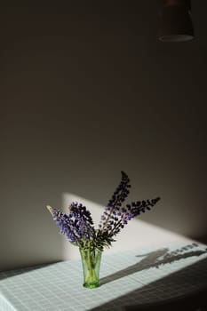 summer flowers purple lupins in vase on the table in sunlight. summer still life with blue lupines bouquet.